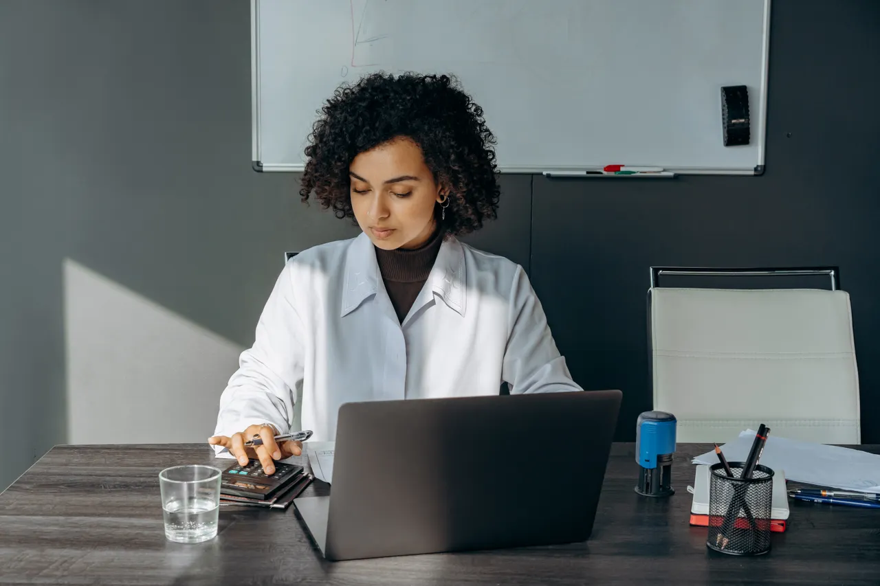 Professional working on a laptop with documents on the desk